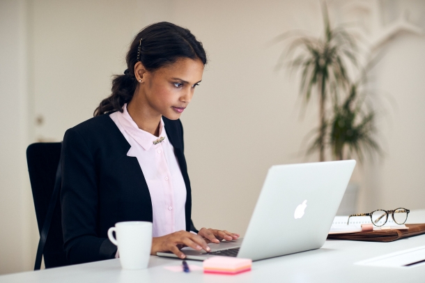 Kvinna sitter och arbetar vid sin laptop
